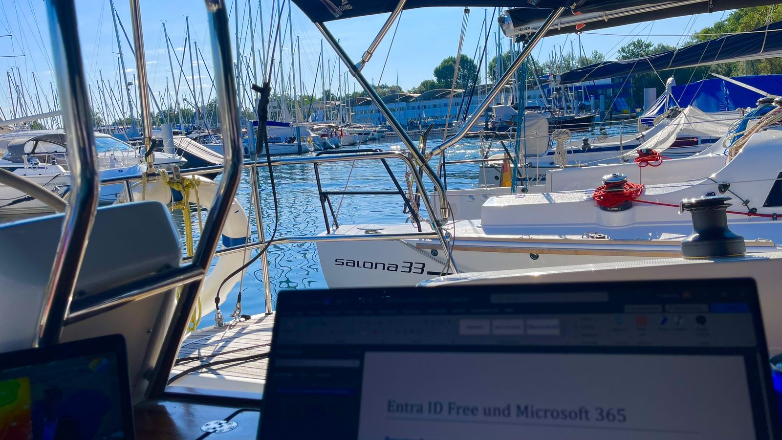 Arbeiten mit Laptop an Bord eines Segelboots im Hafen