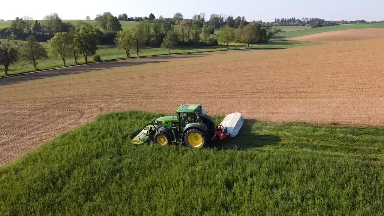 Traktor mit Mähwerk bei der Feldarbeit aus der Vogelperspektive